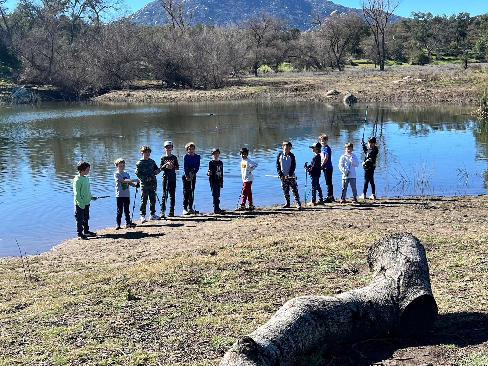 Boys holding fishing rods beside a lake
